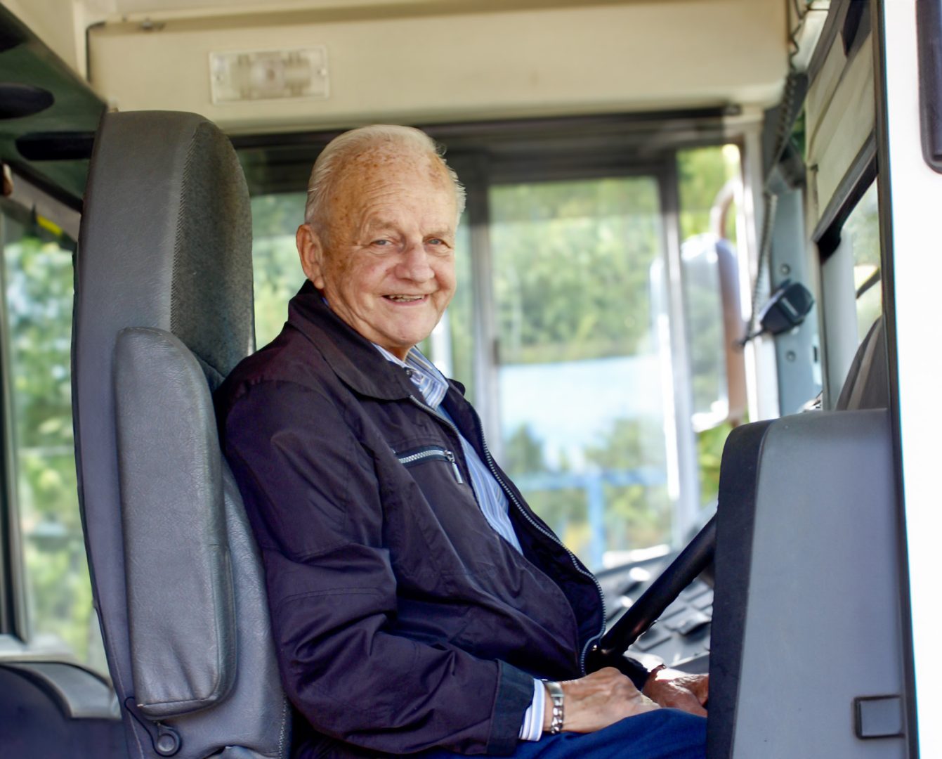 chauffeur d'autobus âgé de 87 ans souriant au volant de son véhicule